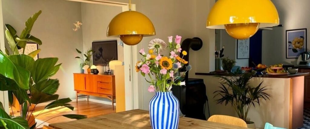 Sala de jantar decorada com plantas e luminárias pendentes.